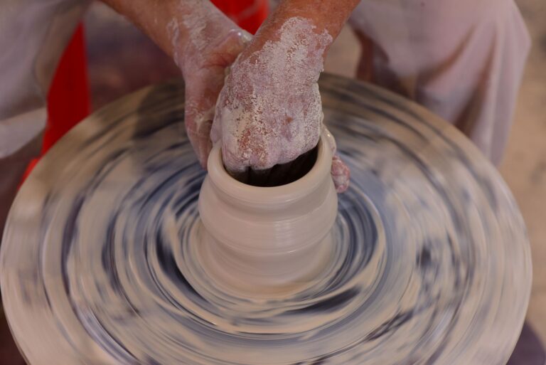 Hands expertly shaping clay on a pottery wheel
